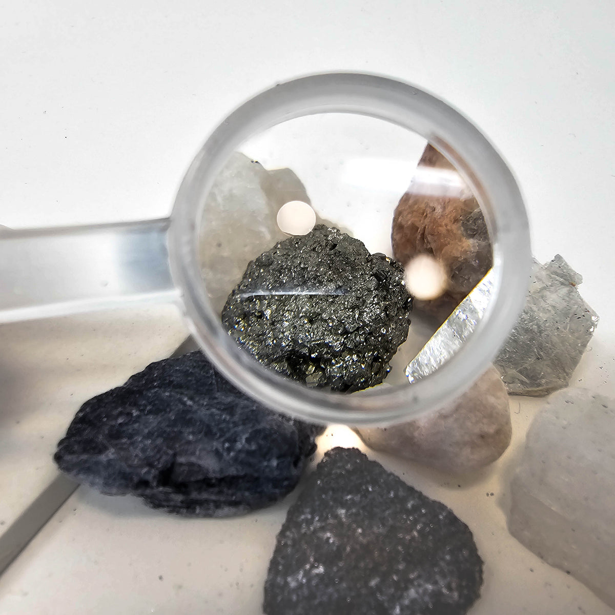 Mineral hardness test kit from the USA – magnifier over a mineral specimen