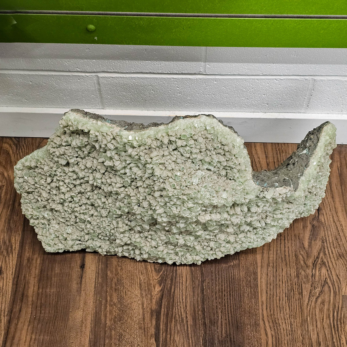 Green apophyllite crystal plate from Maharashtra, India – side profile on a wooden table