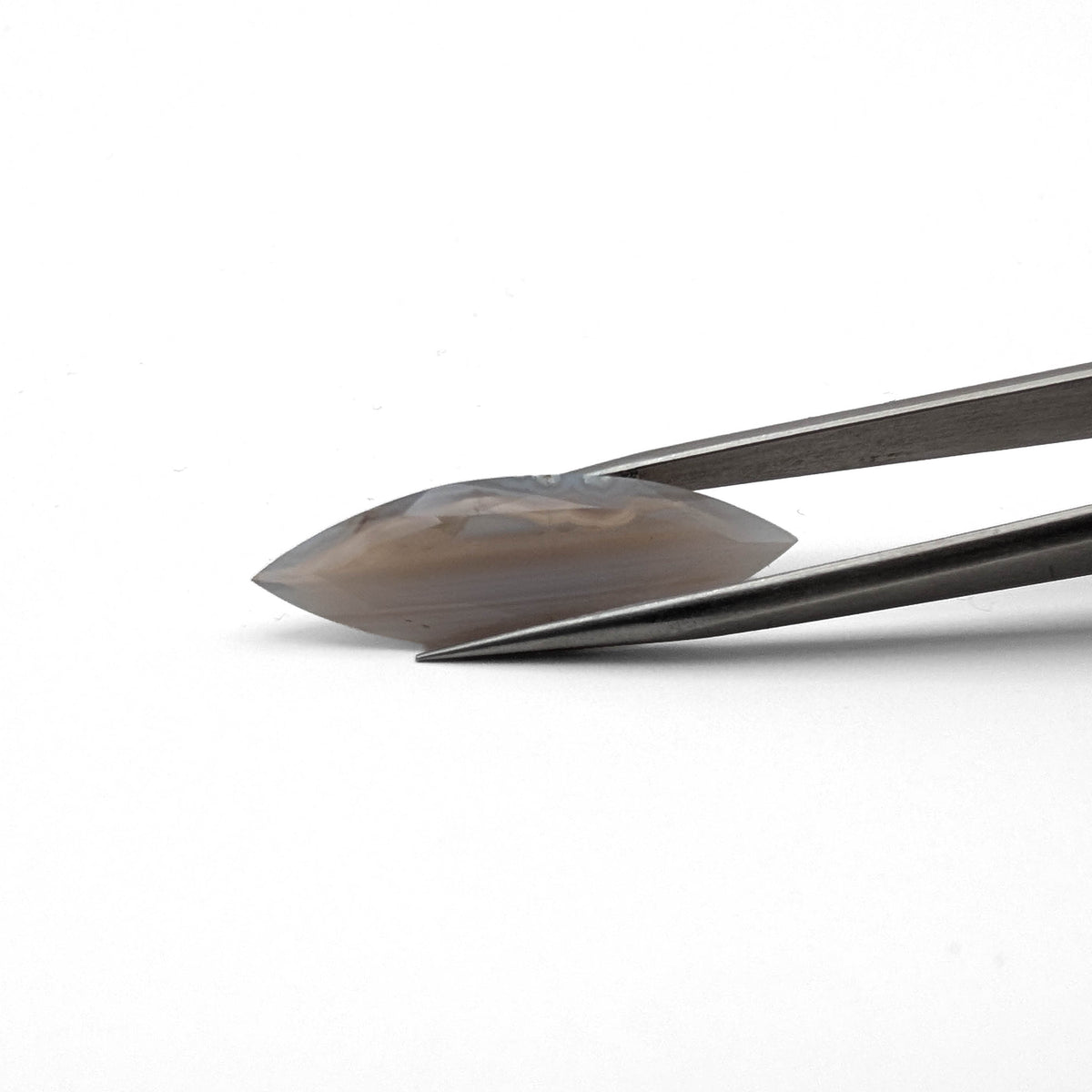 Grey Fortification Agate faceted marquise gemstone, 9.40ct, from BC, Canada, held in tweezers, view 2 of 10