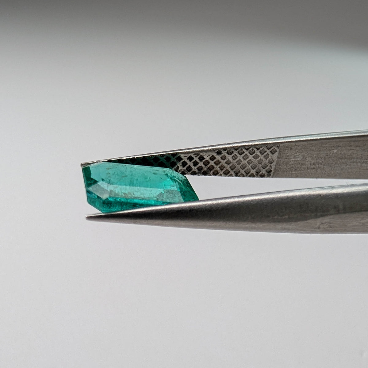 Emerald faceted emerald cut gemstone, 1.09ct, held in tweezers, view 11 of 11