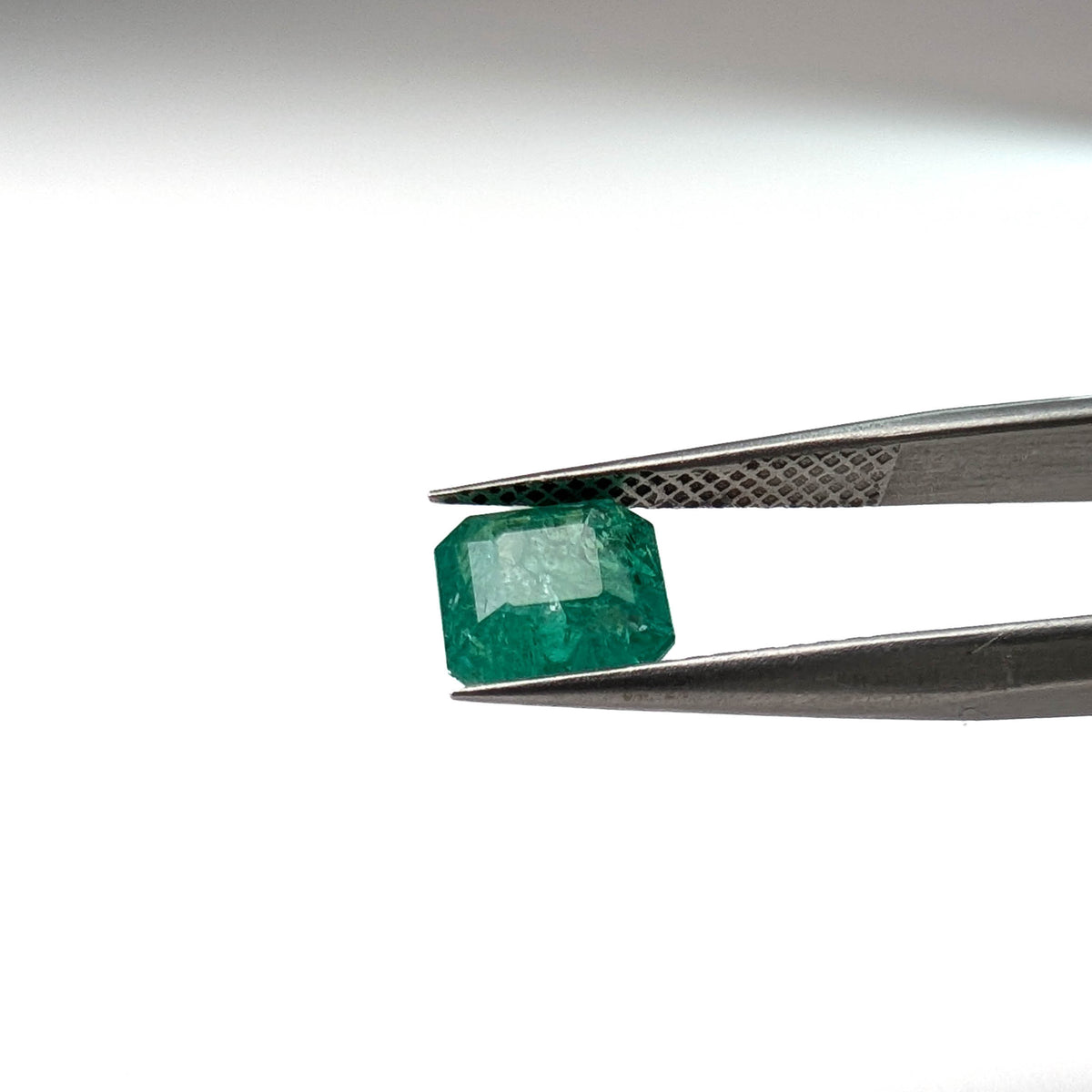 Emerald faceted emerald cut gemstone, 1.53ct, held in tweezers, view 9 of 12