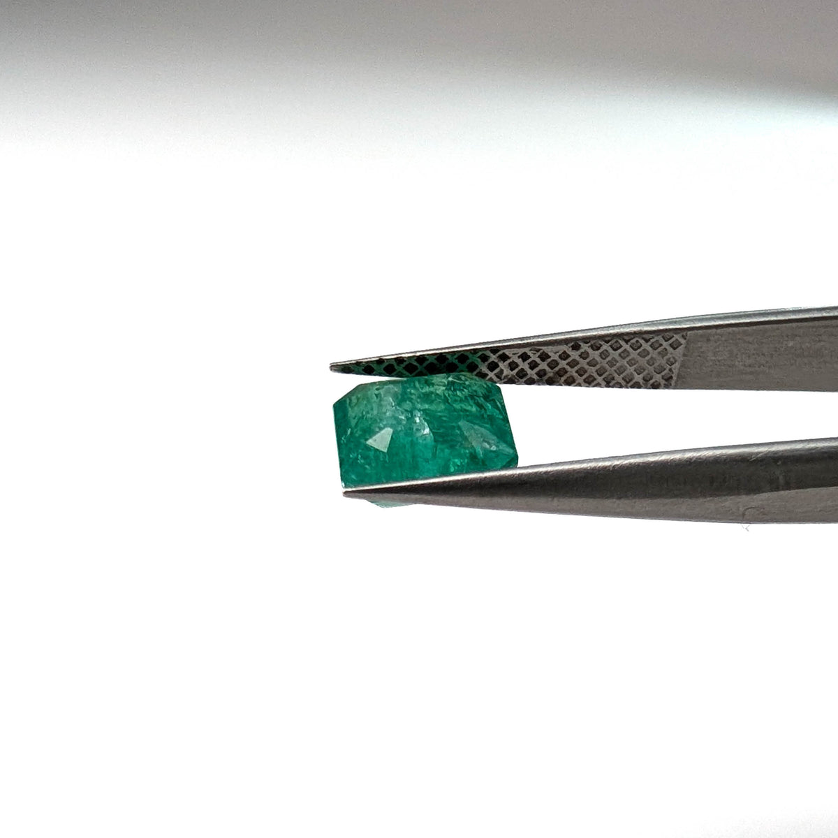 Emerald faceted emerald cut gemstone, 1.53ct, held in tweezers, view 11 of 12