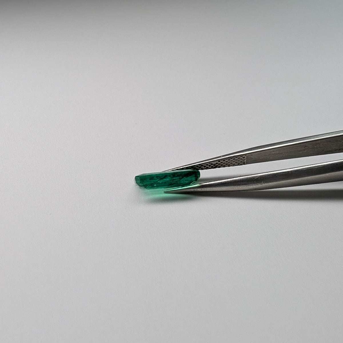 Emerald faceted emerald cut gemstone, 2.04ct, held in tweezers, view 11 of 11