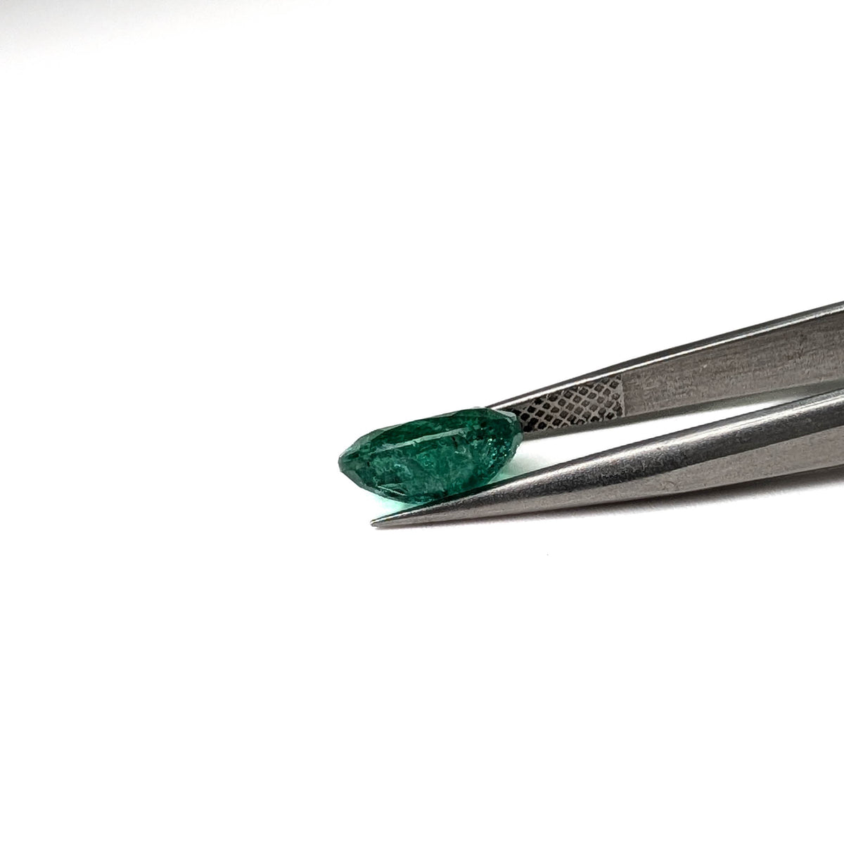 Emerald faceted oval cut gemstone, 2.45ct, held in tweezers, view 18 of 18