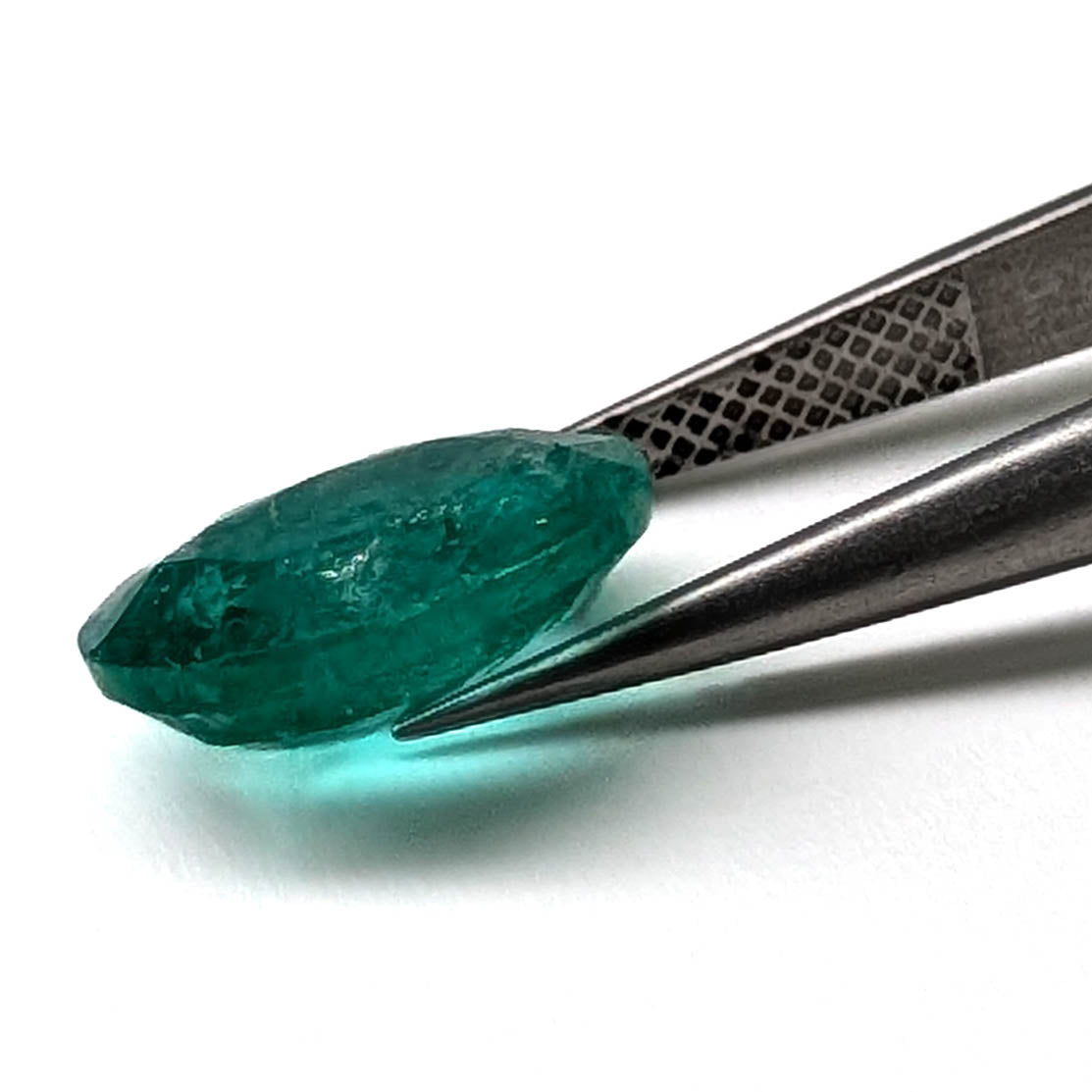 Emerald faceted oval cut gemstone, 3.55ct, held in tweezers, view 8 of 9