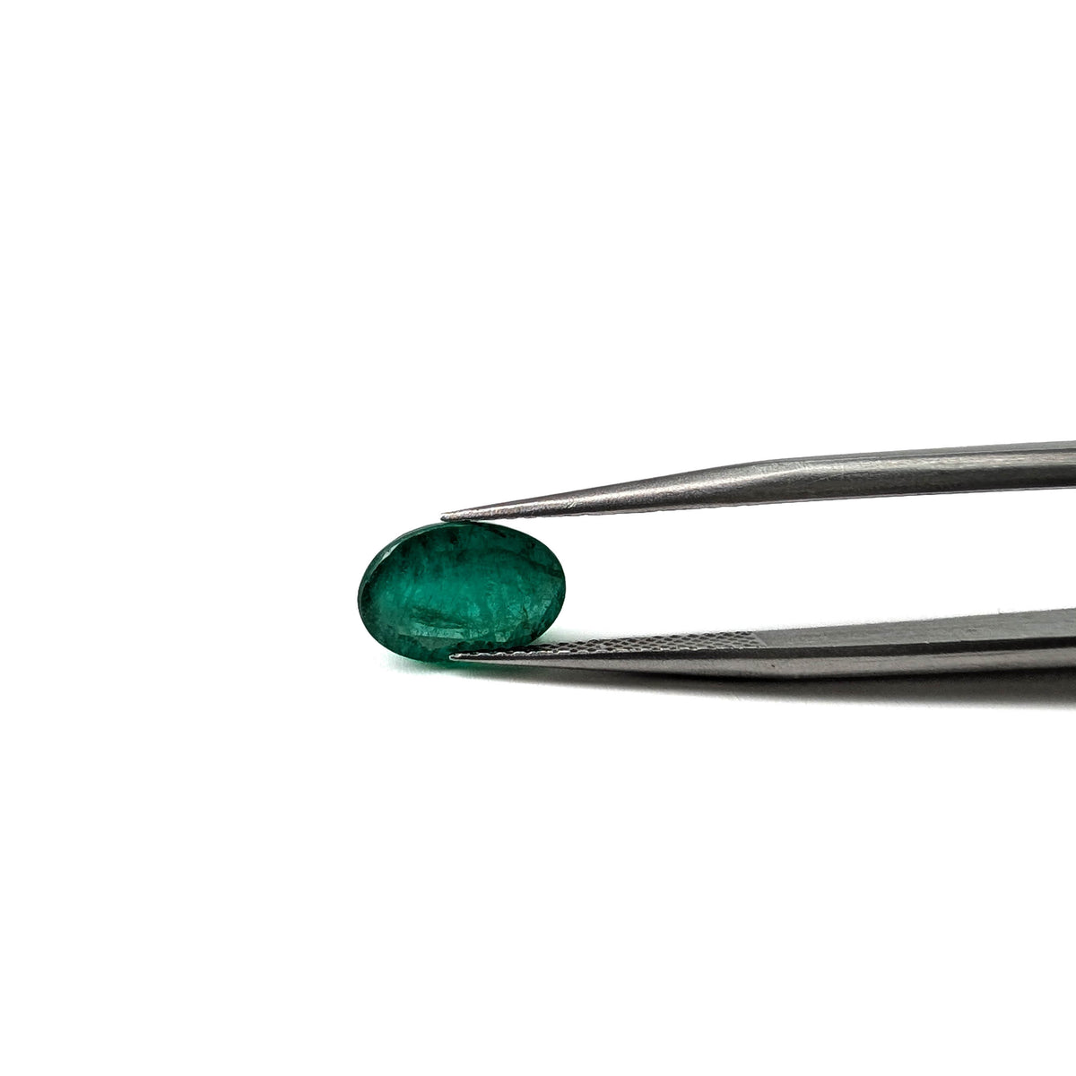 Emerald faceted oval gemstone, 1.92ct, held in tweezers, side view, view 11 of 12