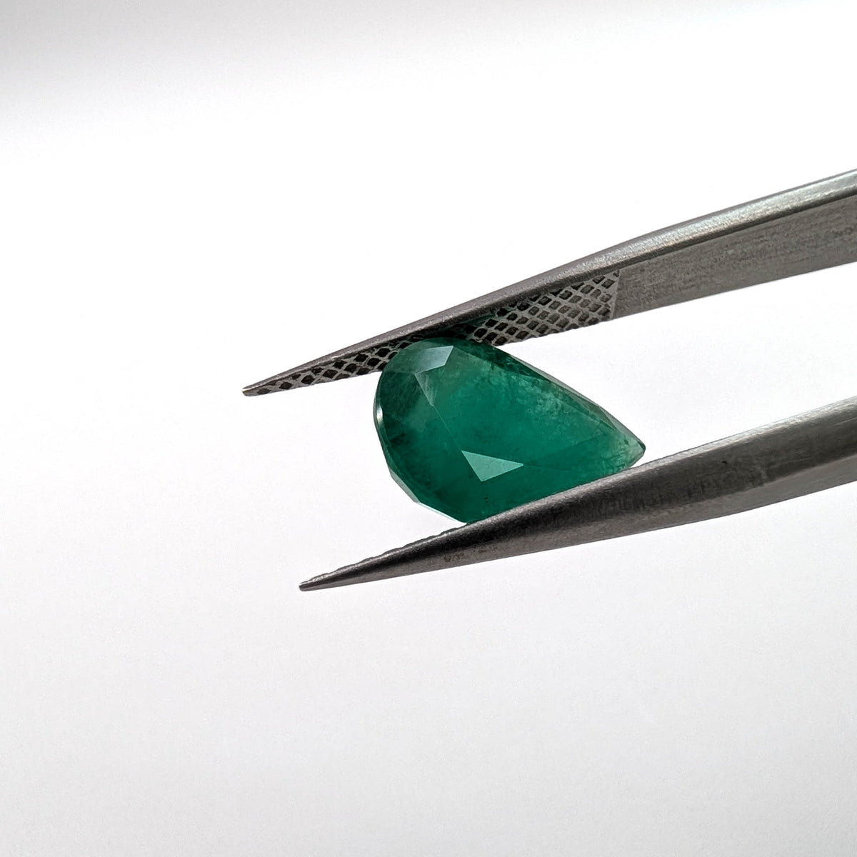 Emerald faceted pear cut gemstone, 2.52ct, held in tweezers, view 8 of 9