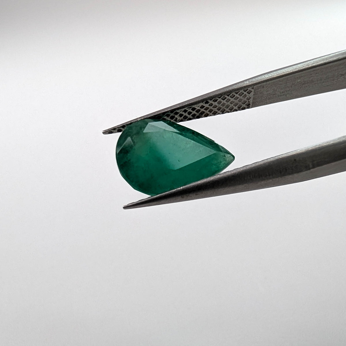 Emerald faceted pear cut gemstone, 2.52ct, held in tweezers, view 9 of 9