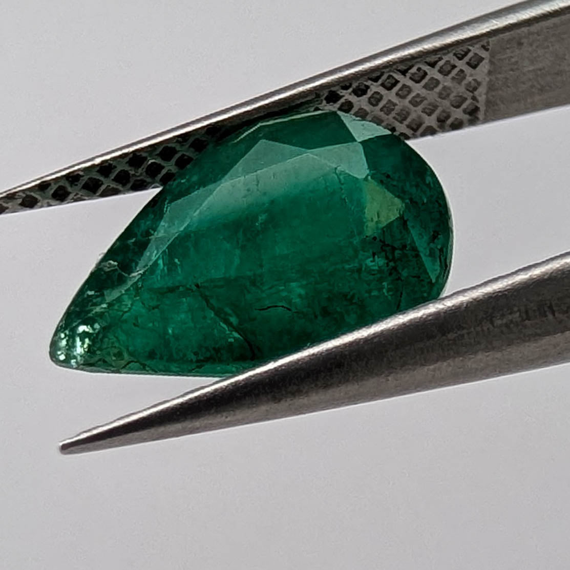 Emerald faceted pear cut gemstone, 2.66ct, held in tweezers, view 13 of 13