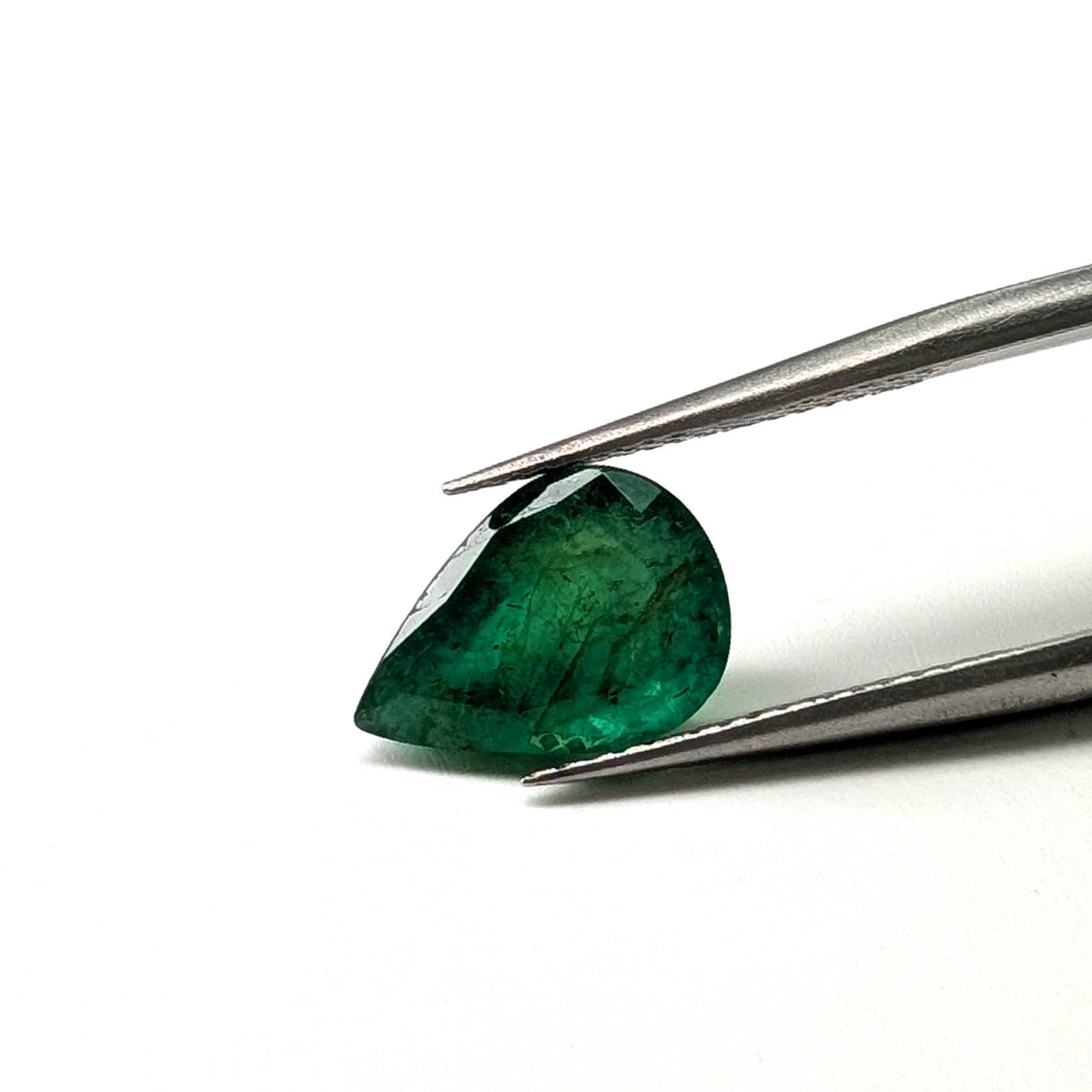 Emerald faceted pear cut gemstone, 2.82ct, held in tweezers, view 2 of 12
