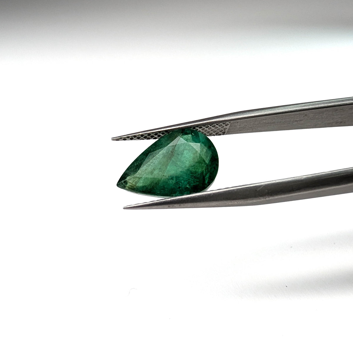 Emerald faceted pear cut gemstone, 3.50ct, held in tweezers, view 2 of 11