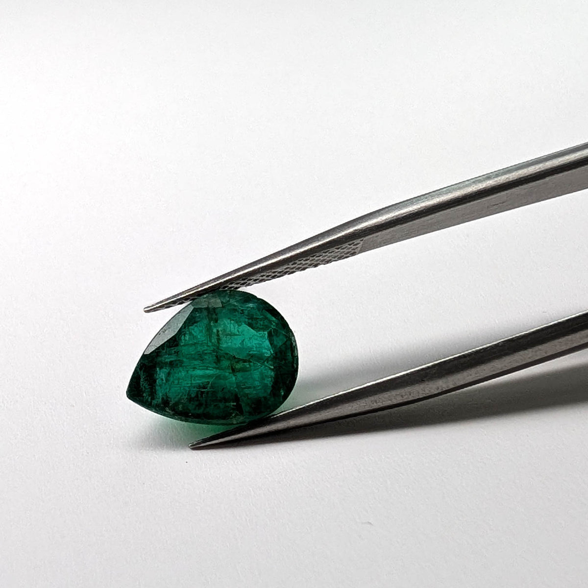 Emerald faceted pear cut gemstone, 3.60ct, held in tweezers, view 2 of 8