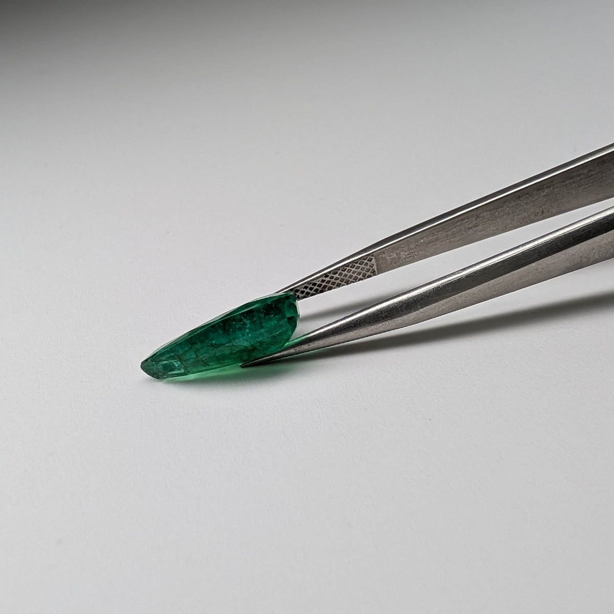 Emerald faceted pear cut gemstone, 3.95ct, held in tweezers, view 13 of 13