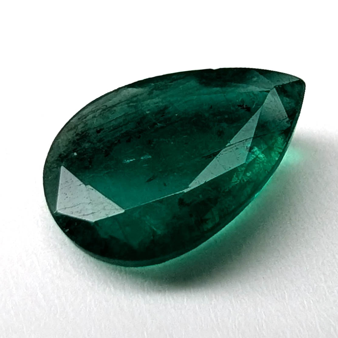 Emerald faceted pear gemstone, 1.60ct, angled face-up view on a white background, view 1 of 11