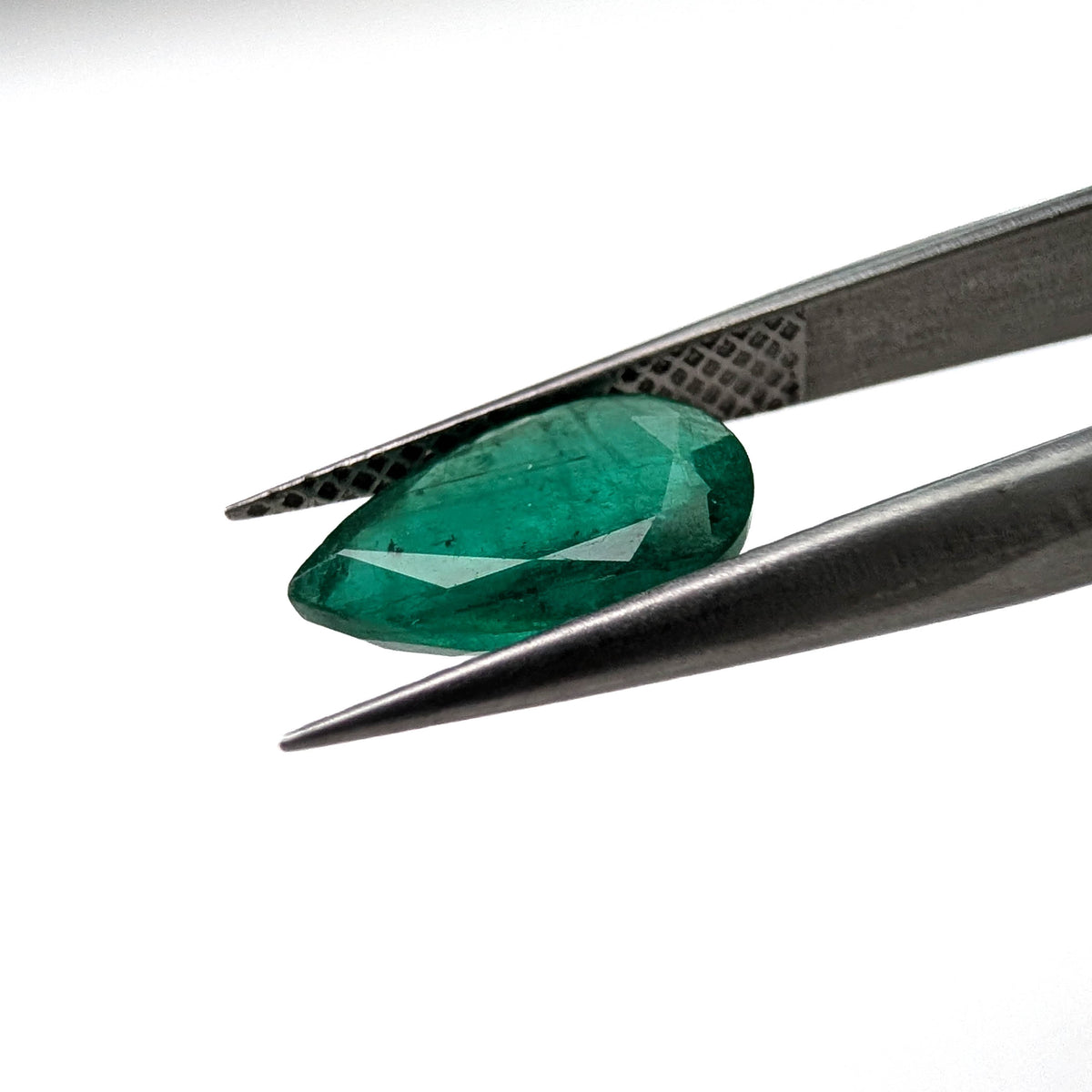 Emerald faceted pear gemstone, 1.60ct, held in tweezers, side view, view 11 of 11