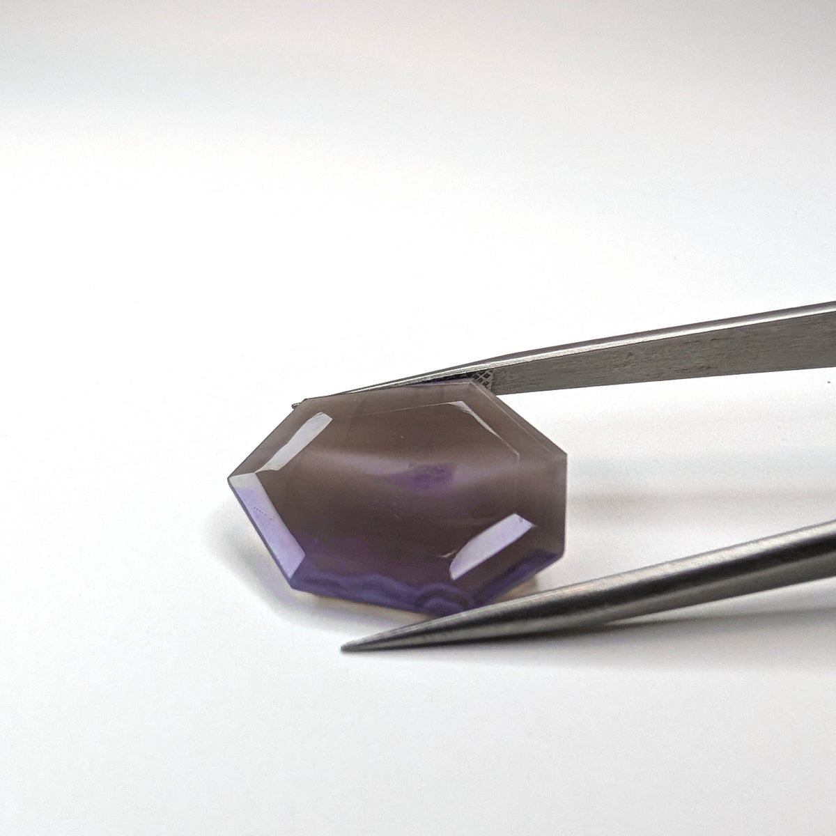 Holly Blue agate faceted freeform step tablet cut gemstone, 12.43ct, from Holley, Oregon, held in tweezers, view 2 of 13