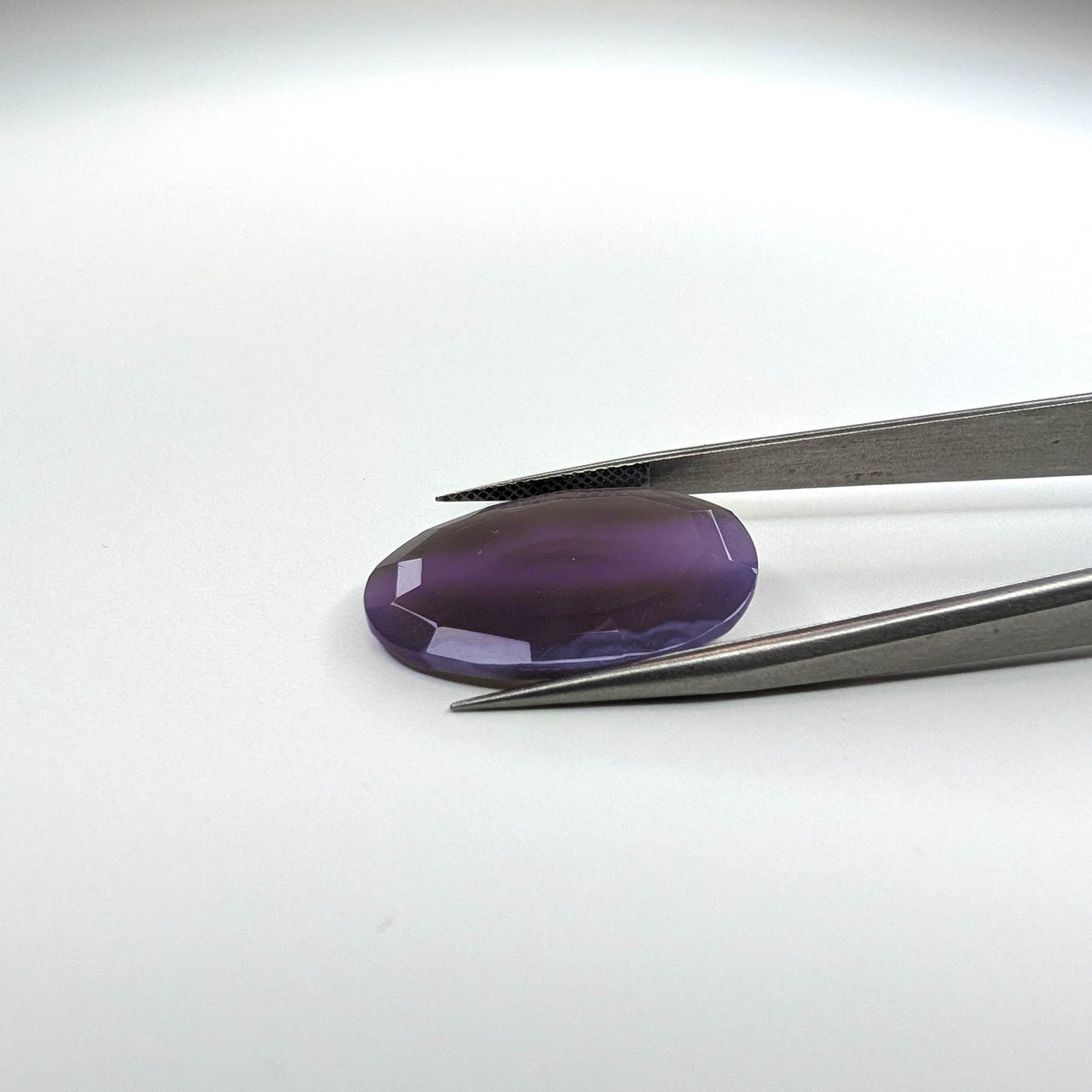 Holly Blue agate faceted egg step tablet cut gemstone, 14.08ct, from Holley, Oregon, held in tweezers, view 7 of 9