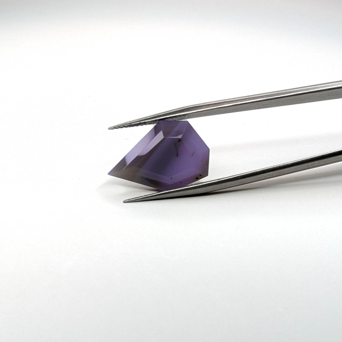 Holly Blue agate faceted freeform step tablet cut gemstone, 8.22ct, from Holley, Oregon, held in tweezers, view 2 of 9