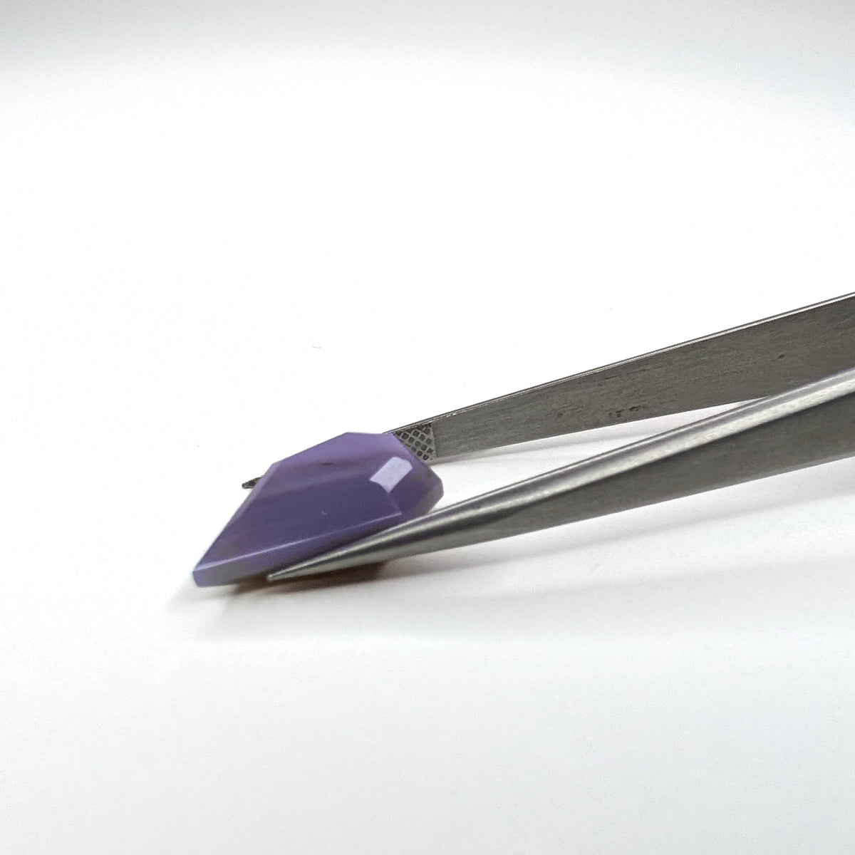 Holly Blue agate faceted freeform step tablet cut gemstone, 8.22ct, from Holley, Oregon, held in tweezers, view 8 of 9