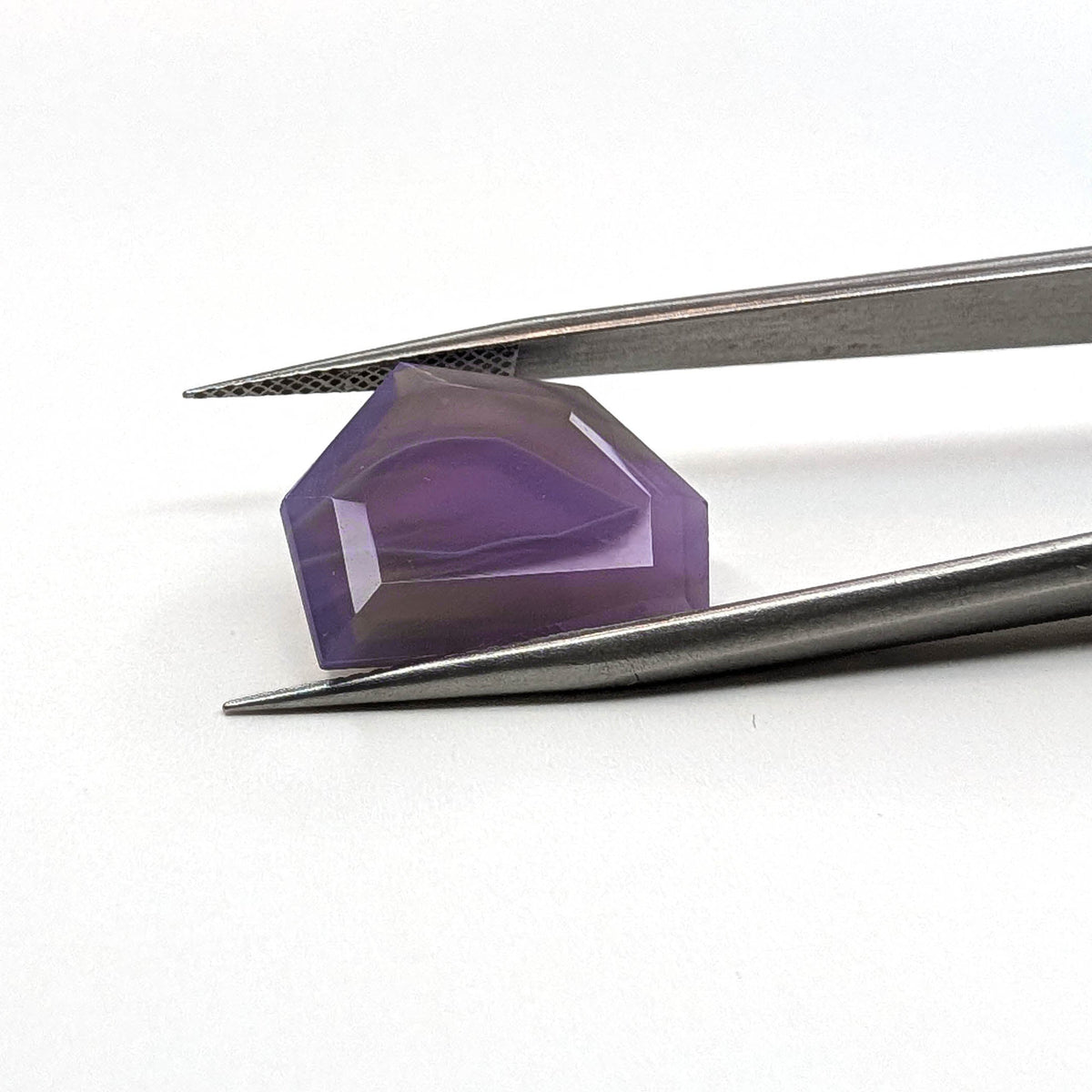 Holly Blue agate faceted freeform step tablet cut gemstone, 8.49ct, from Holley, Oregon, held in tweezers, view 10 of 11
