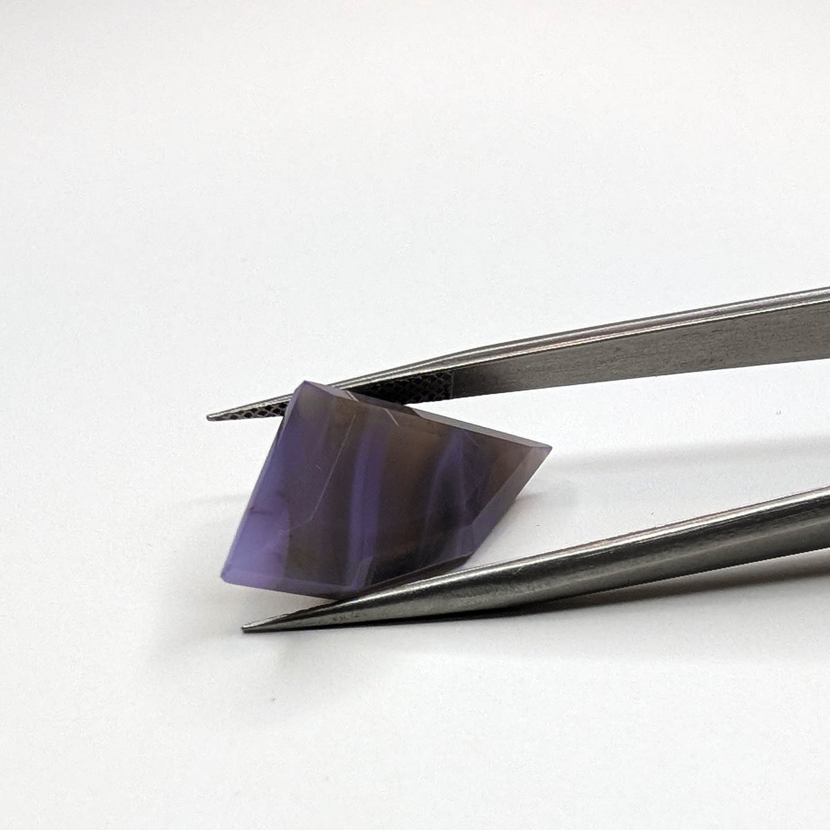Holly Blue agate faceted freeform step tablet cut gemstone, 8.92ct, from Holley, Oregon, held in tweezers, view 2 of 9