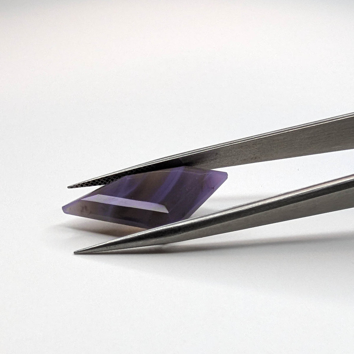 Holly Blue agate faceted freeform step tablet cut gemstone, 8.92ct, from Holley, Oregon, held in tweezers, view 7 of 9