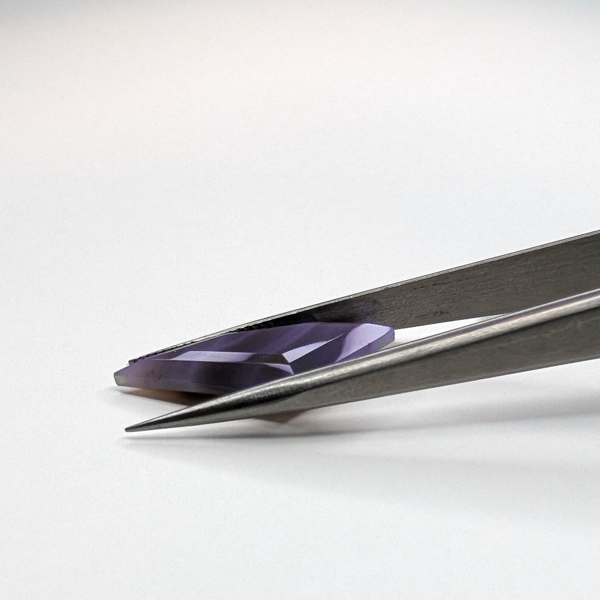 Holly Blue agate faceted freeform step tablet cut gemstone, 8.92ct, from Holley, Oregon, held in tweezers, view 8 of 9