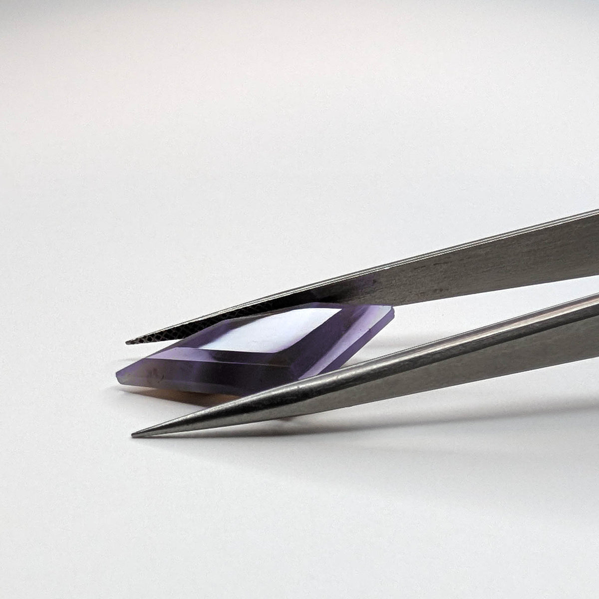 Holly Blue agate faceted freeform step tablet cut gemstone, 8.92ct, from Holley, Oregon, held in tweezers, view 9 of 9