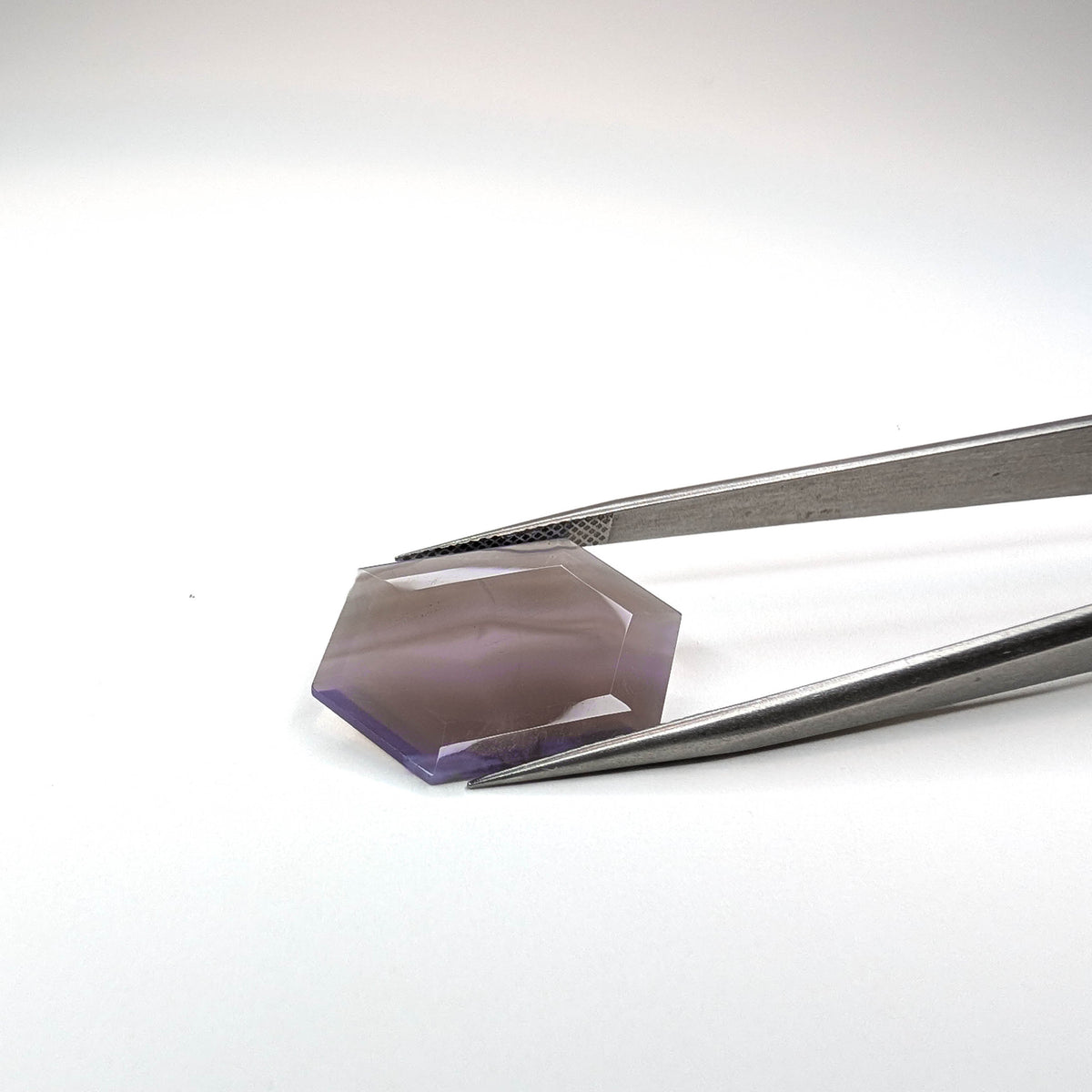 Holly Blue agate faceted freeform step tablet cut gemstone, 8.99ct, from Holley, Oregon, held in tweezers, view 2 of 6