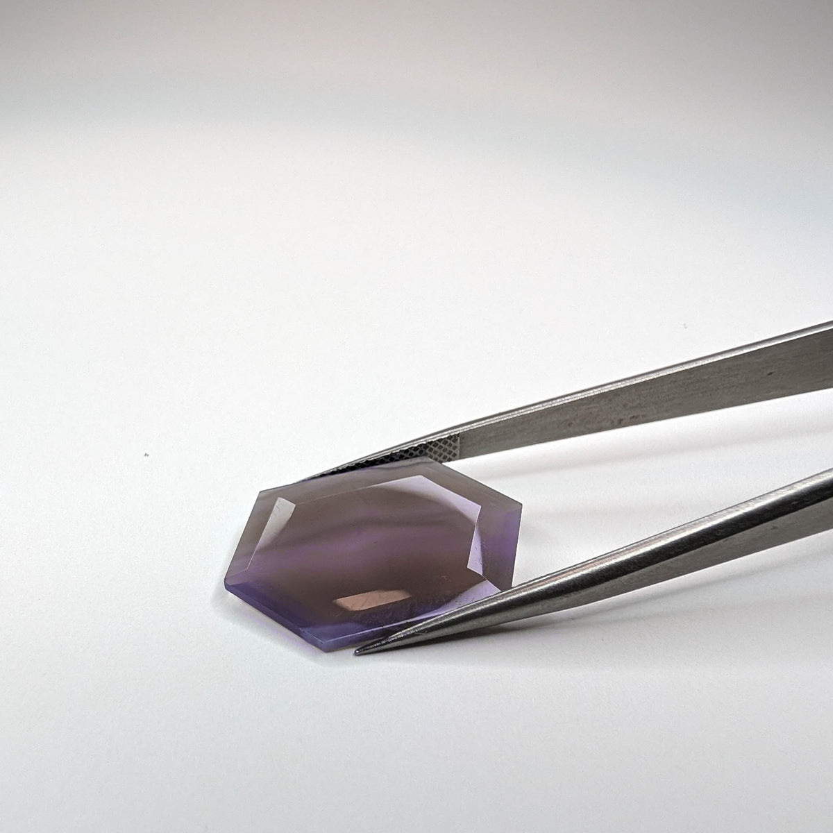 Holly Blue agate faceted freeform step tablet cut gemstone, 8.99ct, from Holley, Oregon, held in tweezers, view 6 of 6