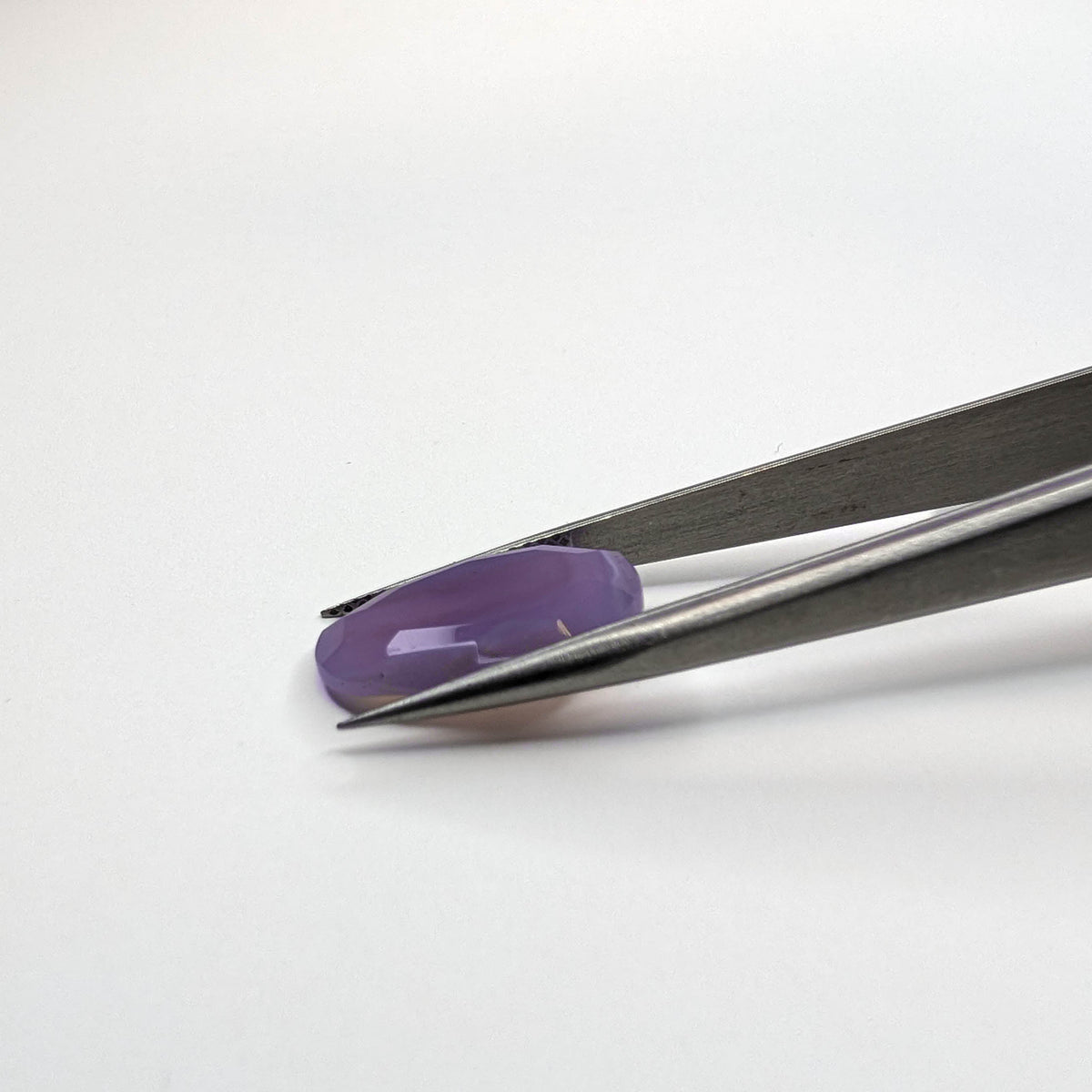 Holly Blue agate faceted egg step tablet cut gemstone, 6.32ct, from Holley, Oregon, held in tweezers, view 8 of 10
