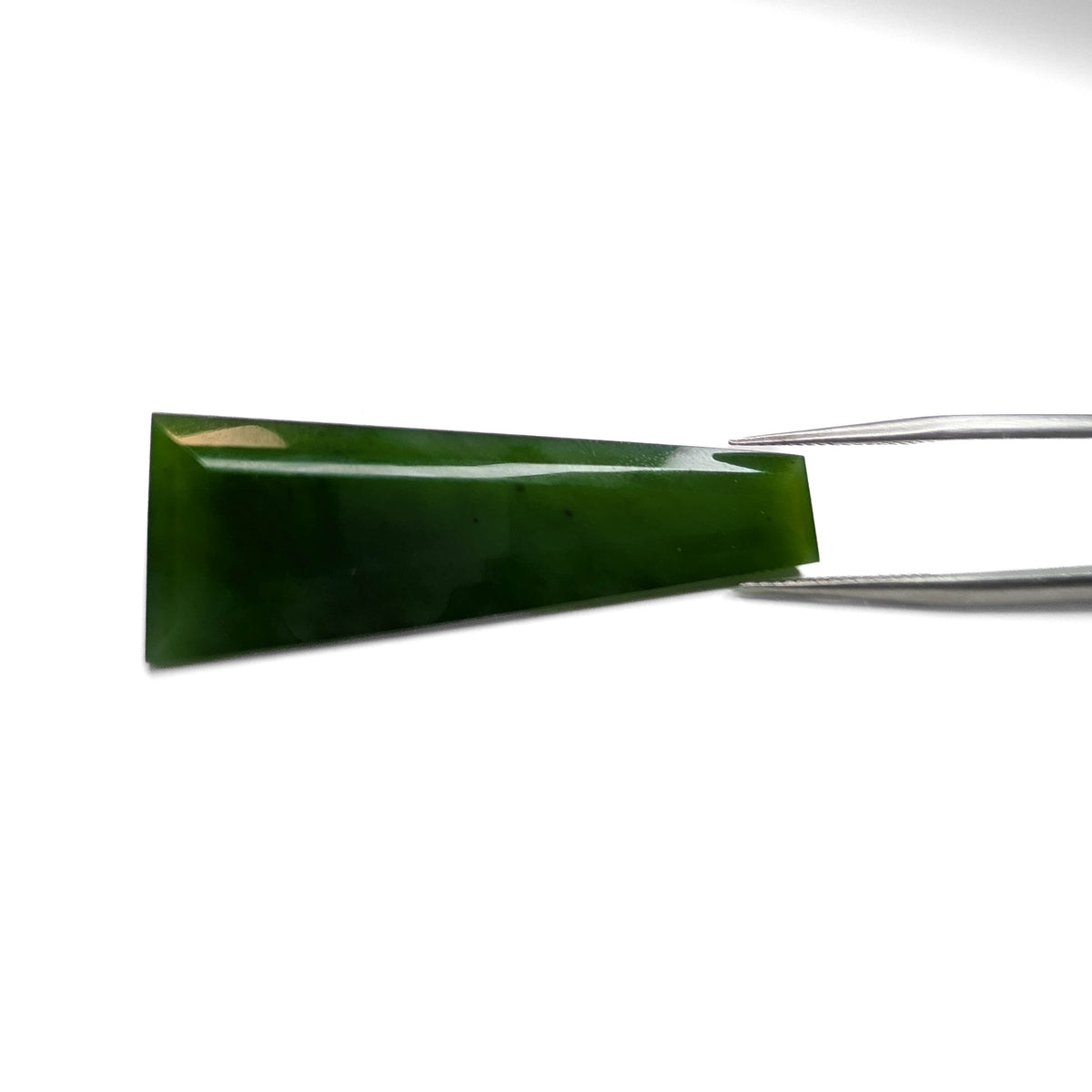 Nephrite Jade faceted tapered baguette gemstone, 33.17ct, held in tweezers