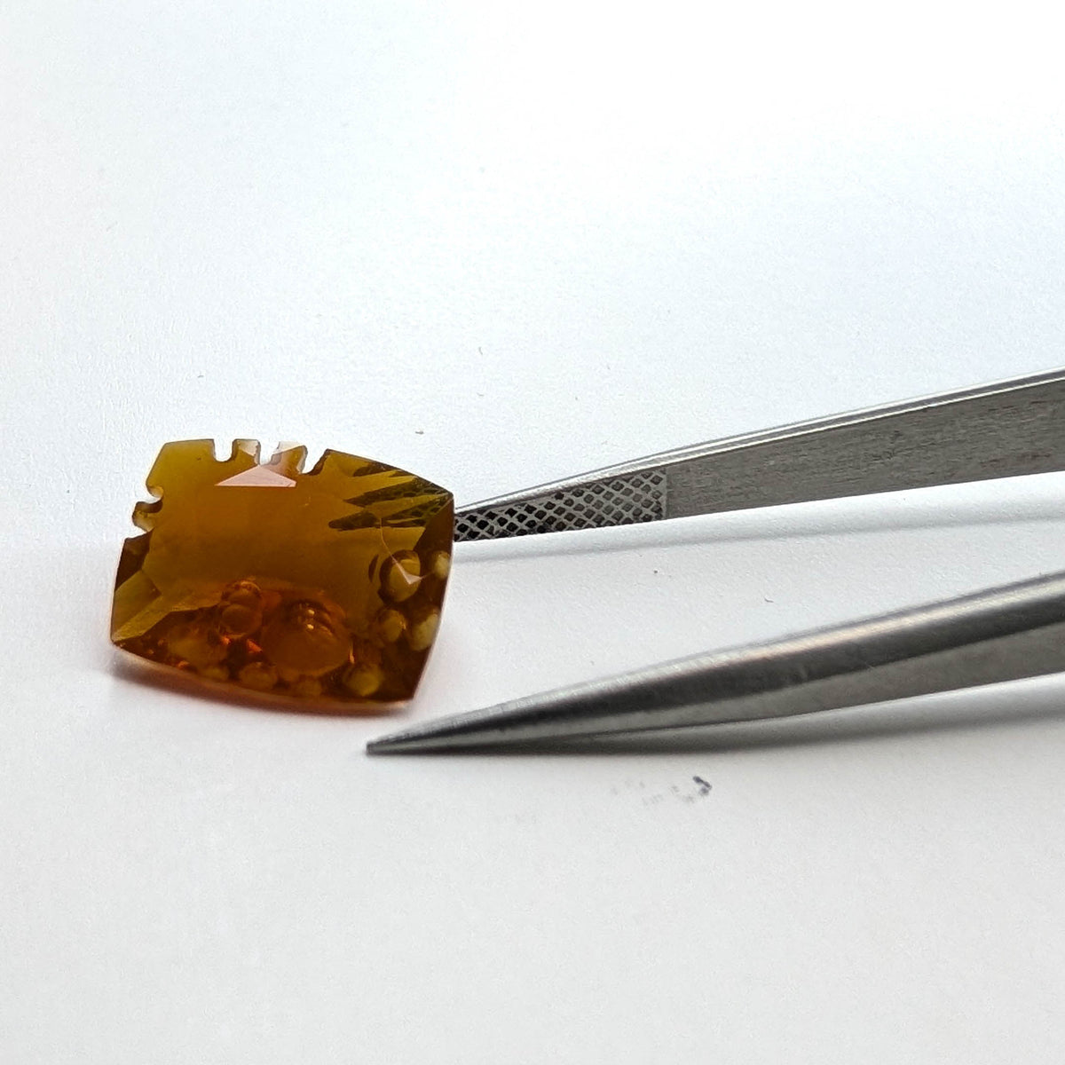 Oregon fire opal faceted cushion fantasy cut gemstone, 4.06ct, held in tweezers, view 2 of 11