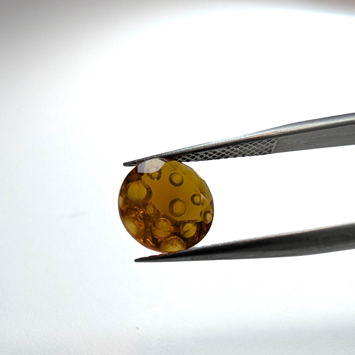 Oregon fire opal faceted round fantasy cut gemstone, 1.82ct, held in tweezers, view 2 of 11