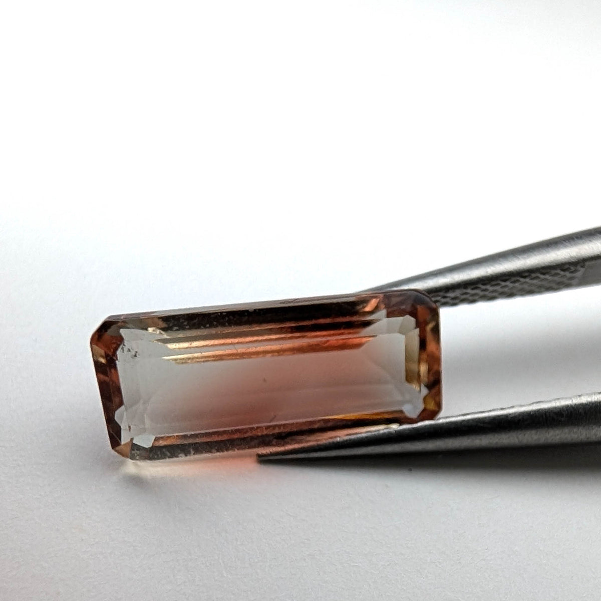 Oregon sunstone faceted emerald gemstone, 3.18ct, held in tweezers, view 2 of 9