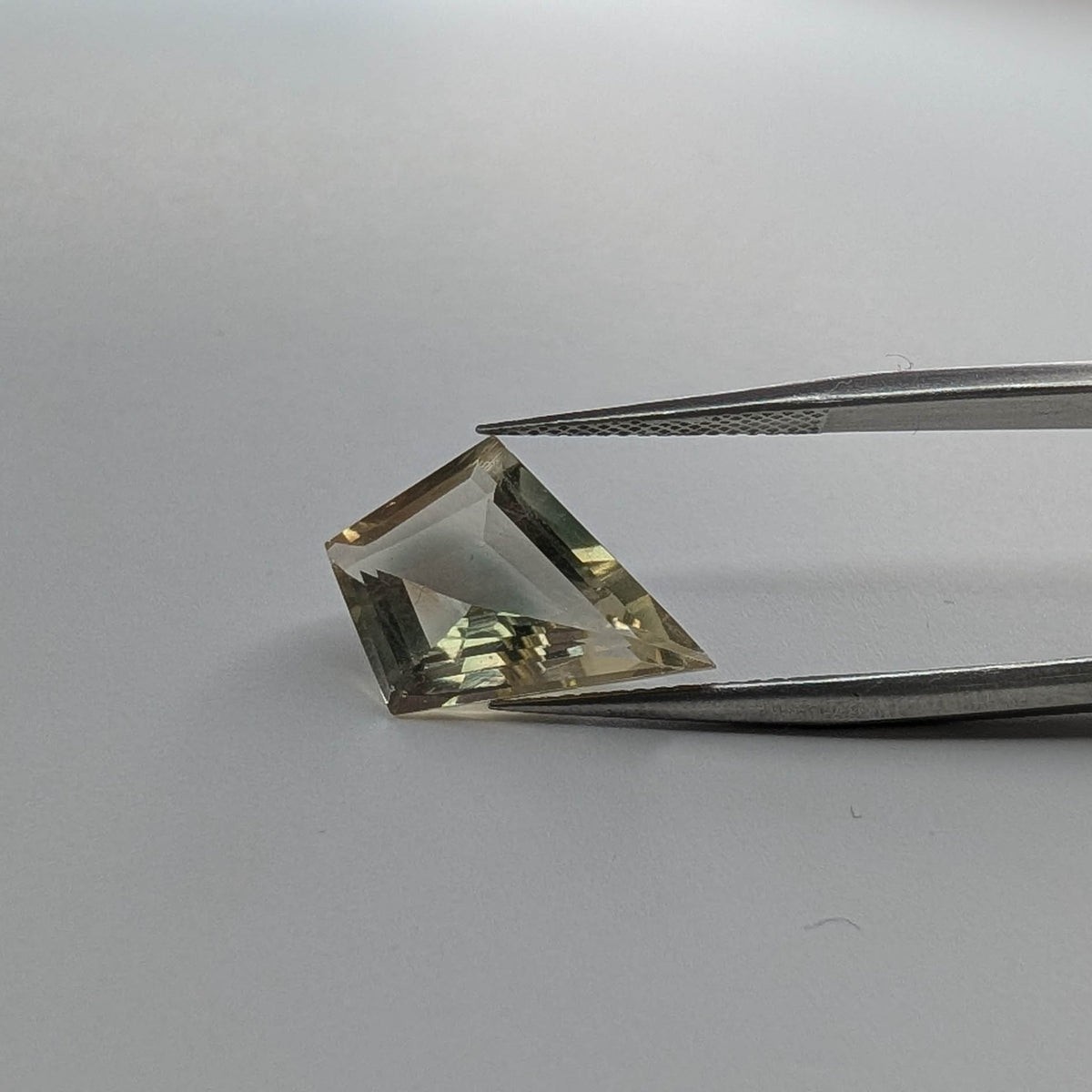 Oregon Sunstone faceted kite step cut gemstone, 3.44ct, from Plush, Oregon, held in tweezers, view 2 of 15