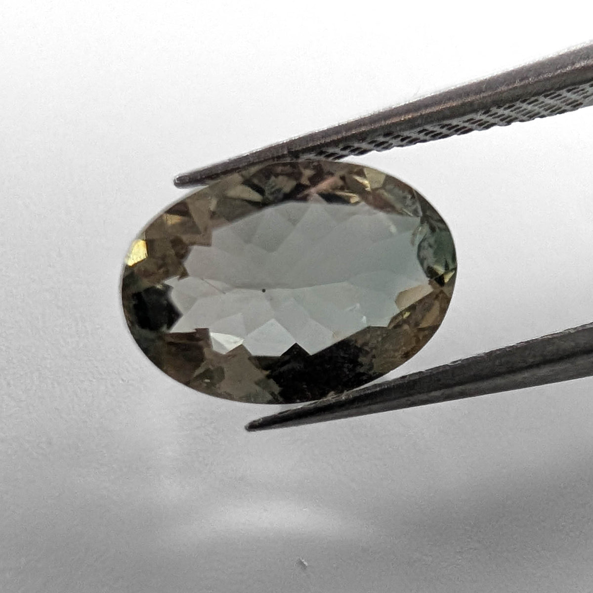 Oregon Sunstone faceted oval cut gemstone, 1.89ct, from Plush, Oregon, held in tweezers, view 2 of 10