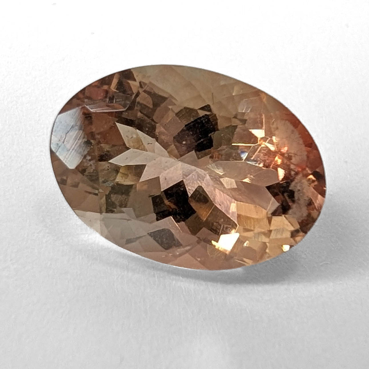 Oregon Sunstone faceted oval cut gemstone, 5.57ct, from Plush, Oregon, on a white background, view 1 of 11