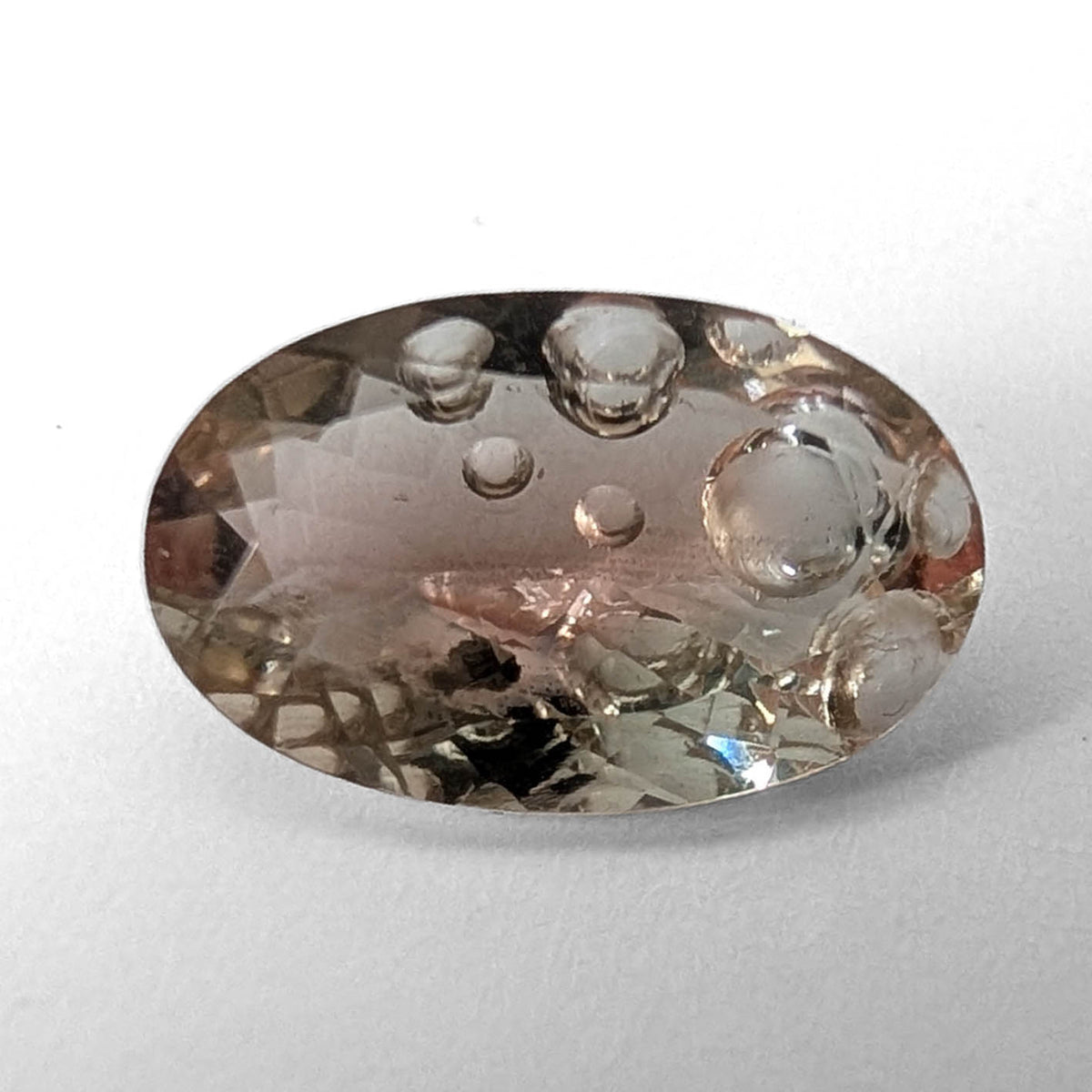 Oregon Sunstone faceted oval fantasy cut gemstone, 3.11ct, from Plush, Oregon, on a white background, view 1 of 15
