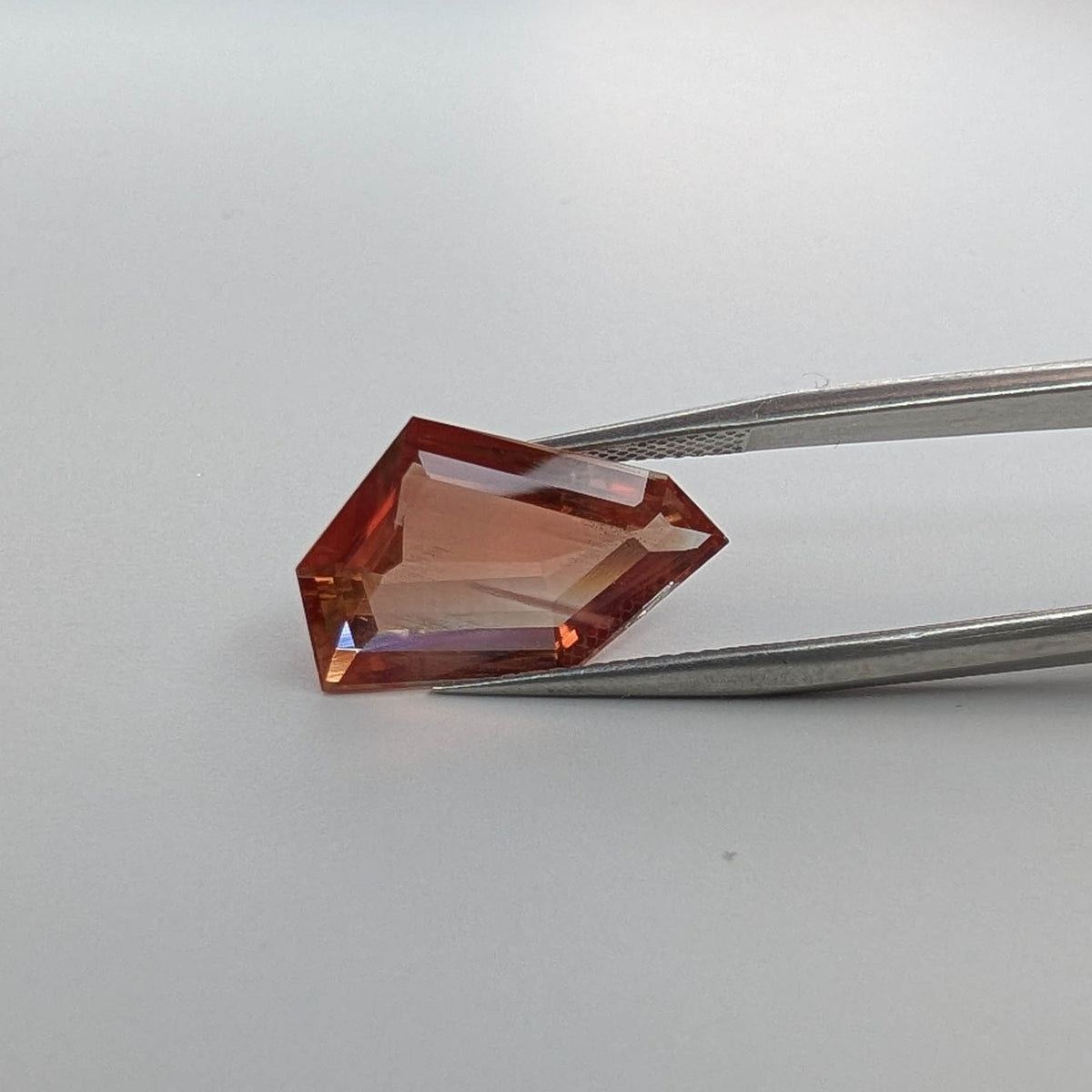 Oregon Sunstone faceted freeform step cut gemstone, 6.70ct, from Plush, Oregon, held in tweezers, view 2 of 10