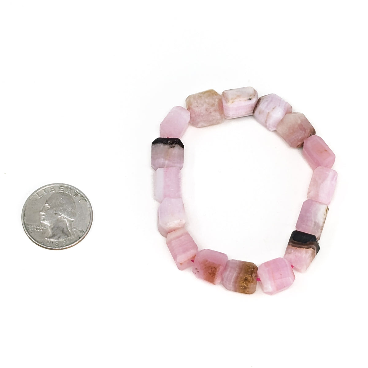 Pink calcite bead bracelet: bracelet beside a coin