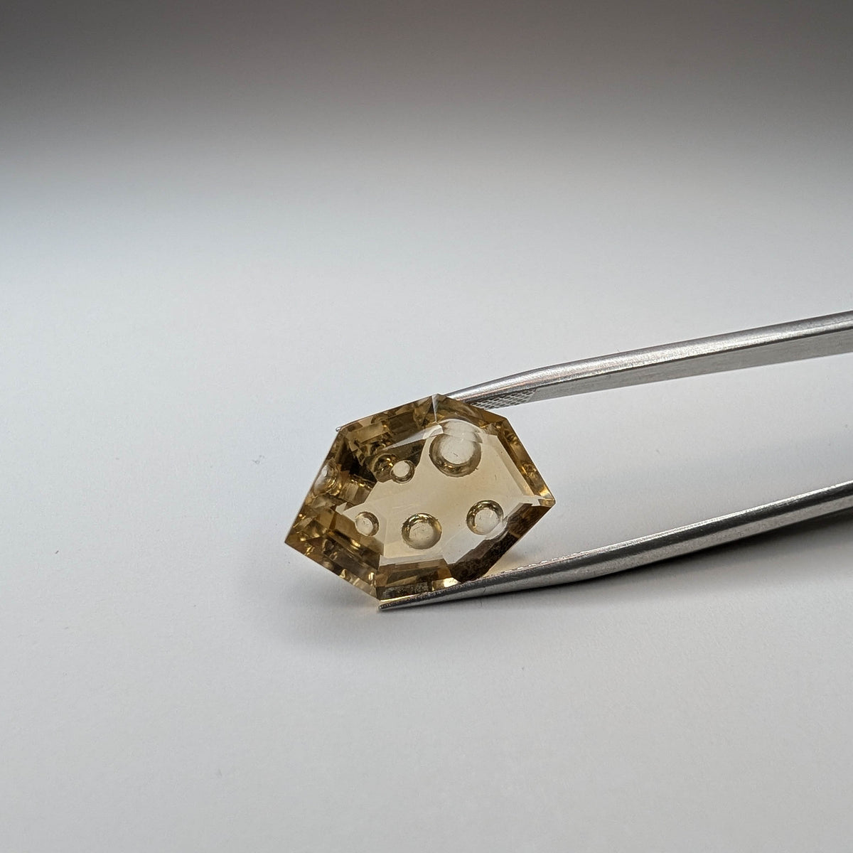 Citrine faceted freeform fantasy cut gemstone held in tweezers, 10.00ct, from Brazil, view 12 of 13