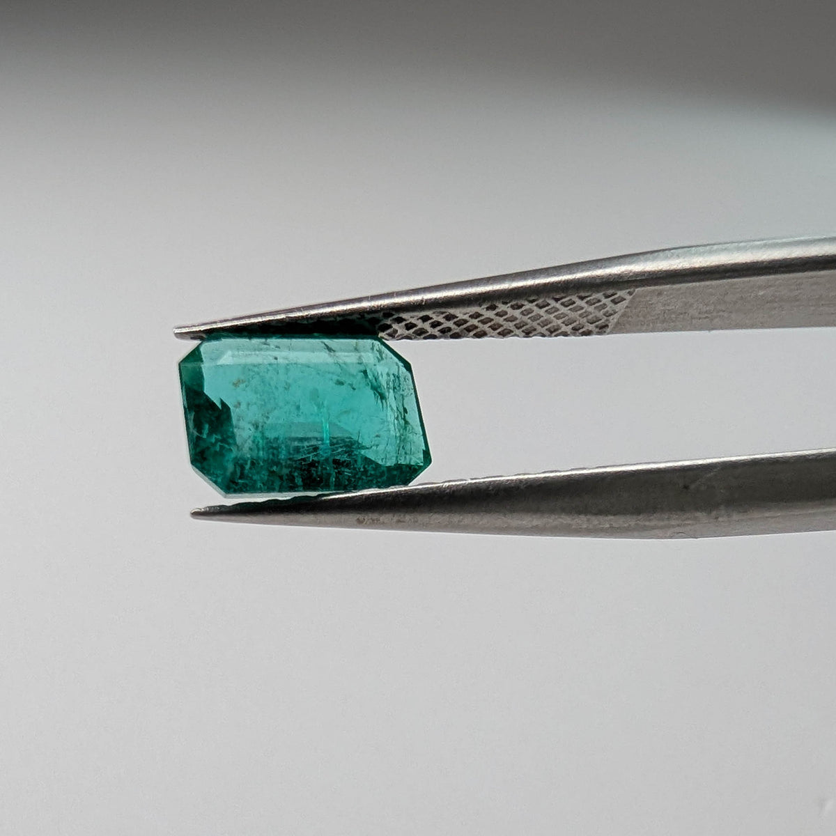 Emerald faceted emerald cut gemstone, 1.09ct, held in tweezers, view 2 of 11