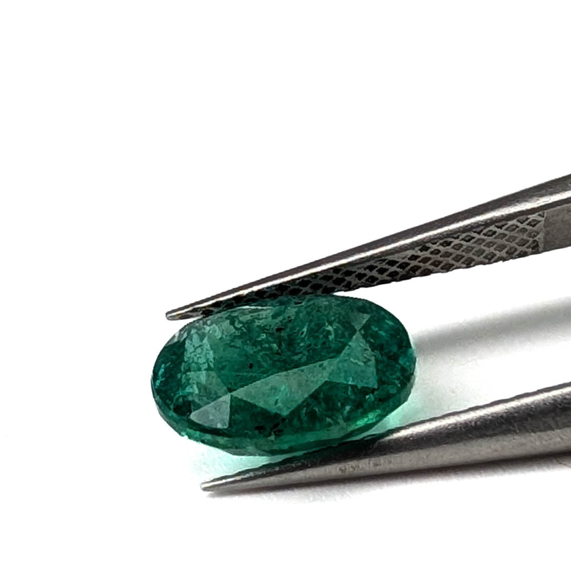 Emerald faceted oval cut gemstone, 2.45ct, held in tweezers, view 17 of 18