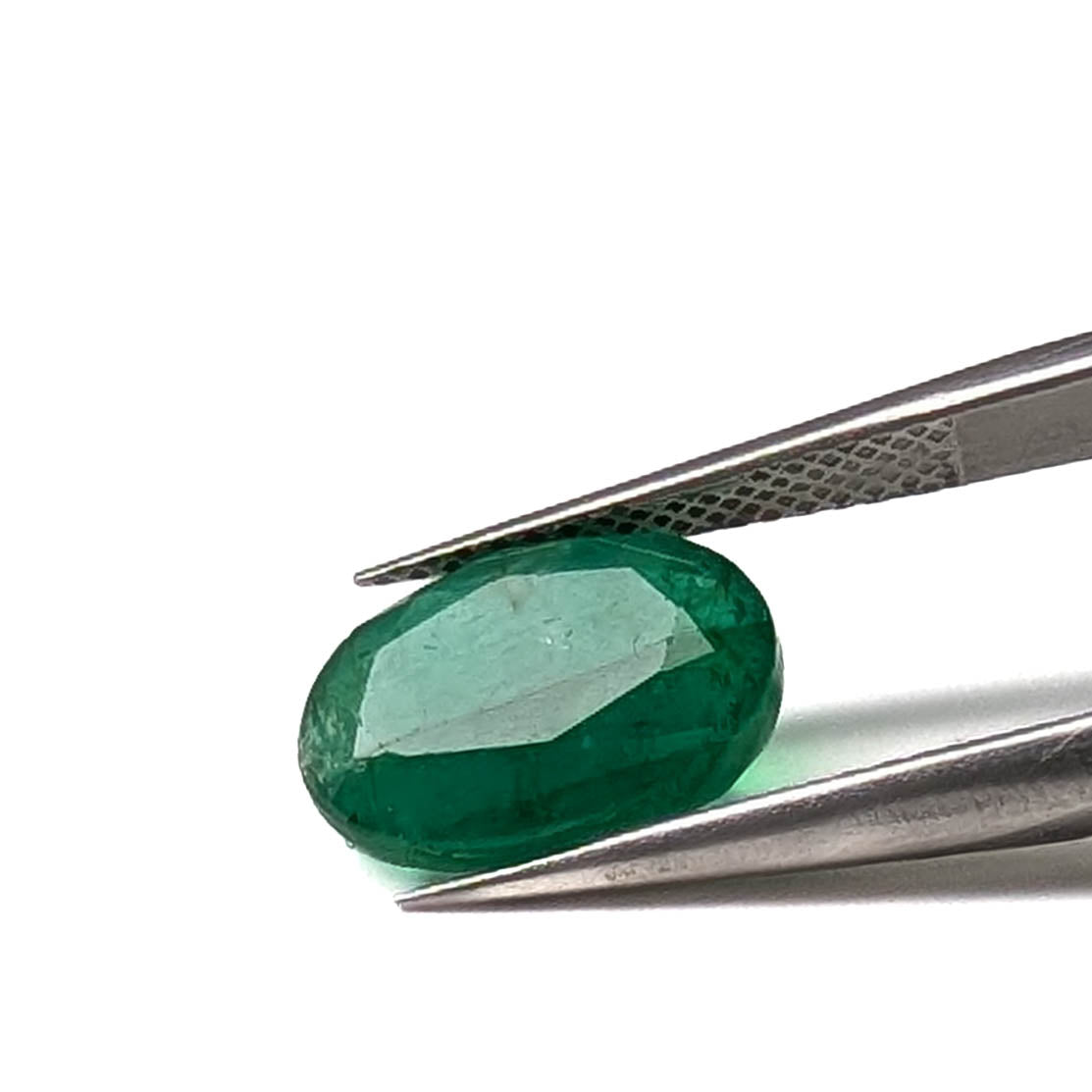 Emerald faceted oval cut gemstone, 3.84ct, held in tweezers, view 9 of 9