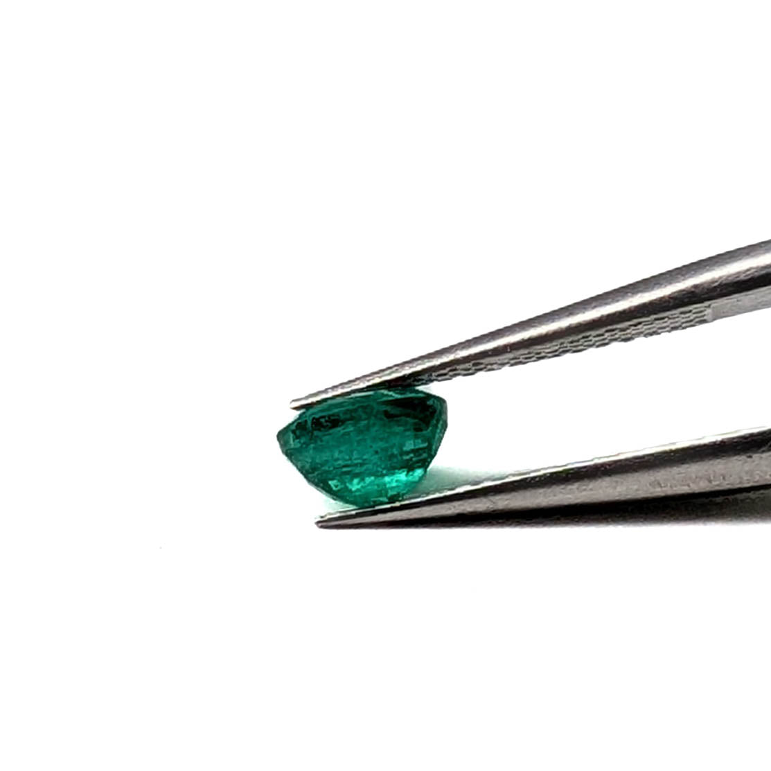 Emerald faceted oval gemstone, 0.73ct, held in tweezers, side view, view 10 of 10