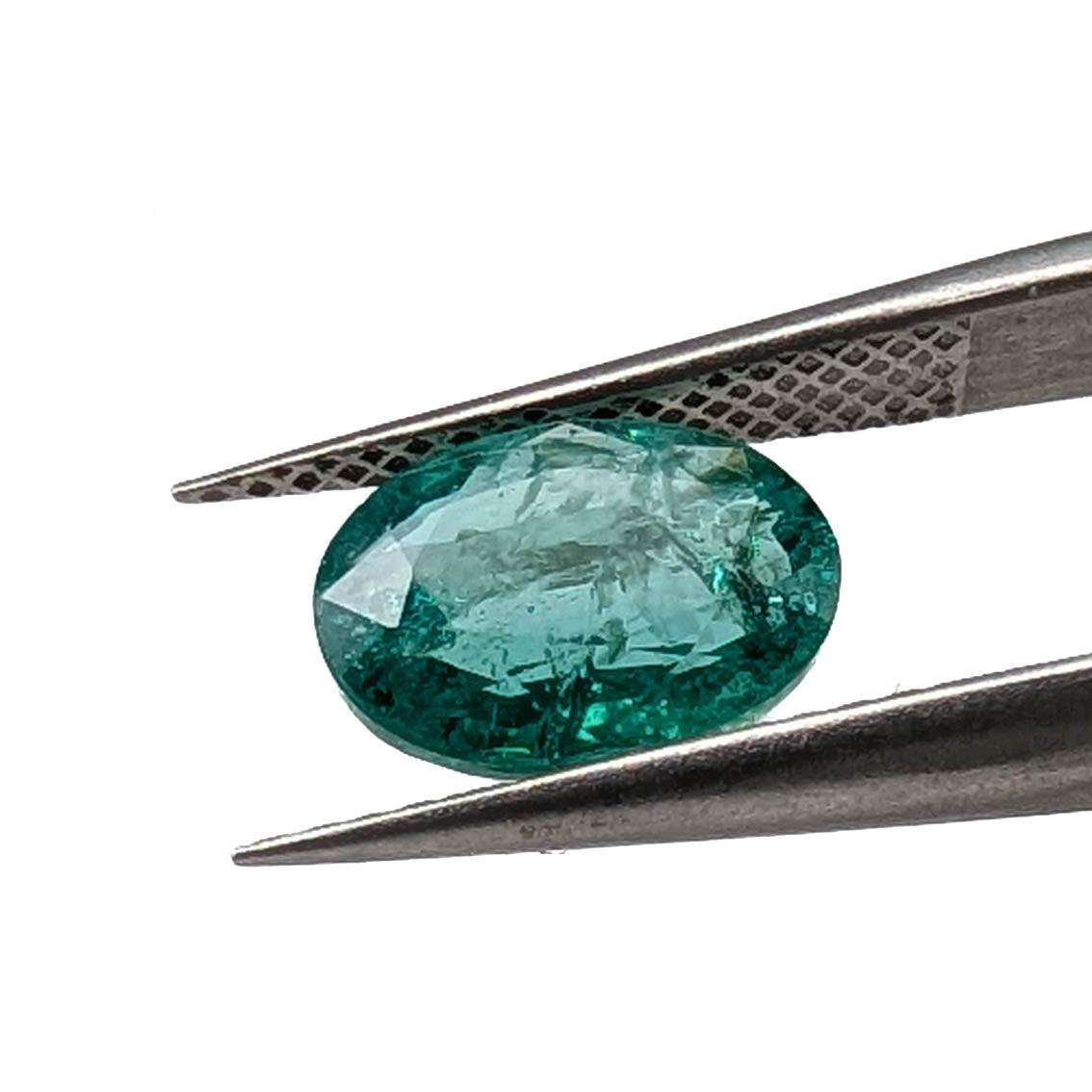 Emerald faceted oval gemstone, 1.90ct, held in tweezers, angled view, view 11 of 13