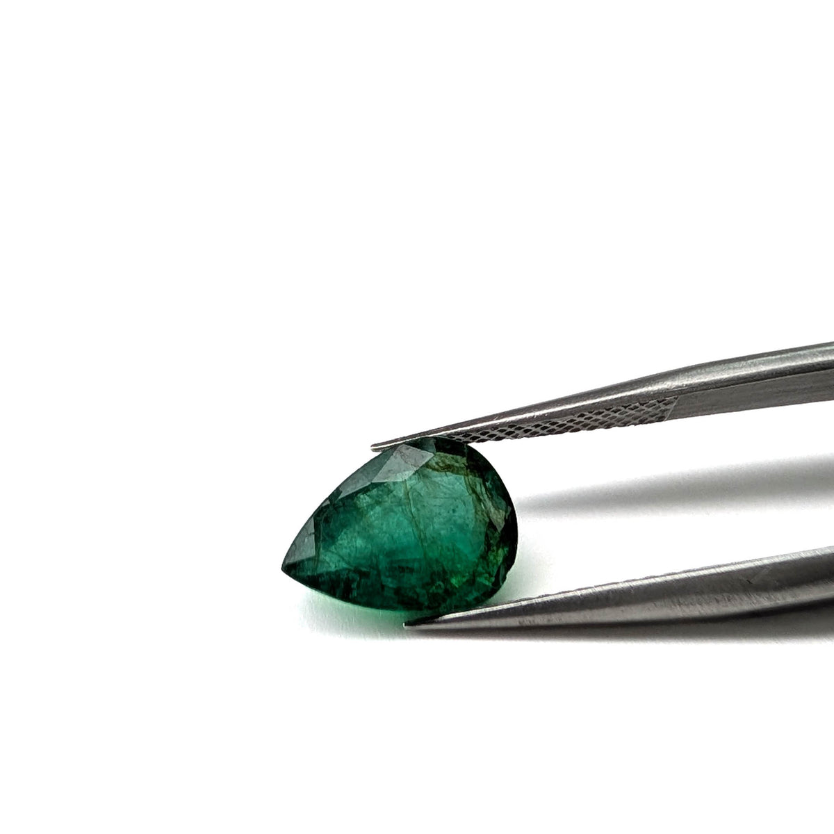 Emerald faceted pear cut gemstone, 2.47ct, held in tweezers, view 2 of 17