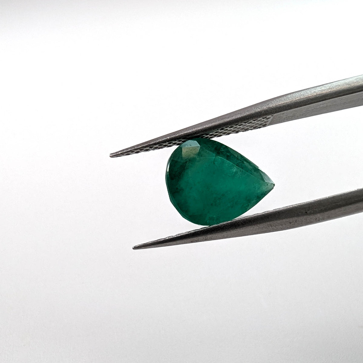 Emerald faceted pear cut gemstone, 2.52ct, held in tweezers, view 2 of 9