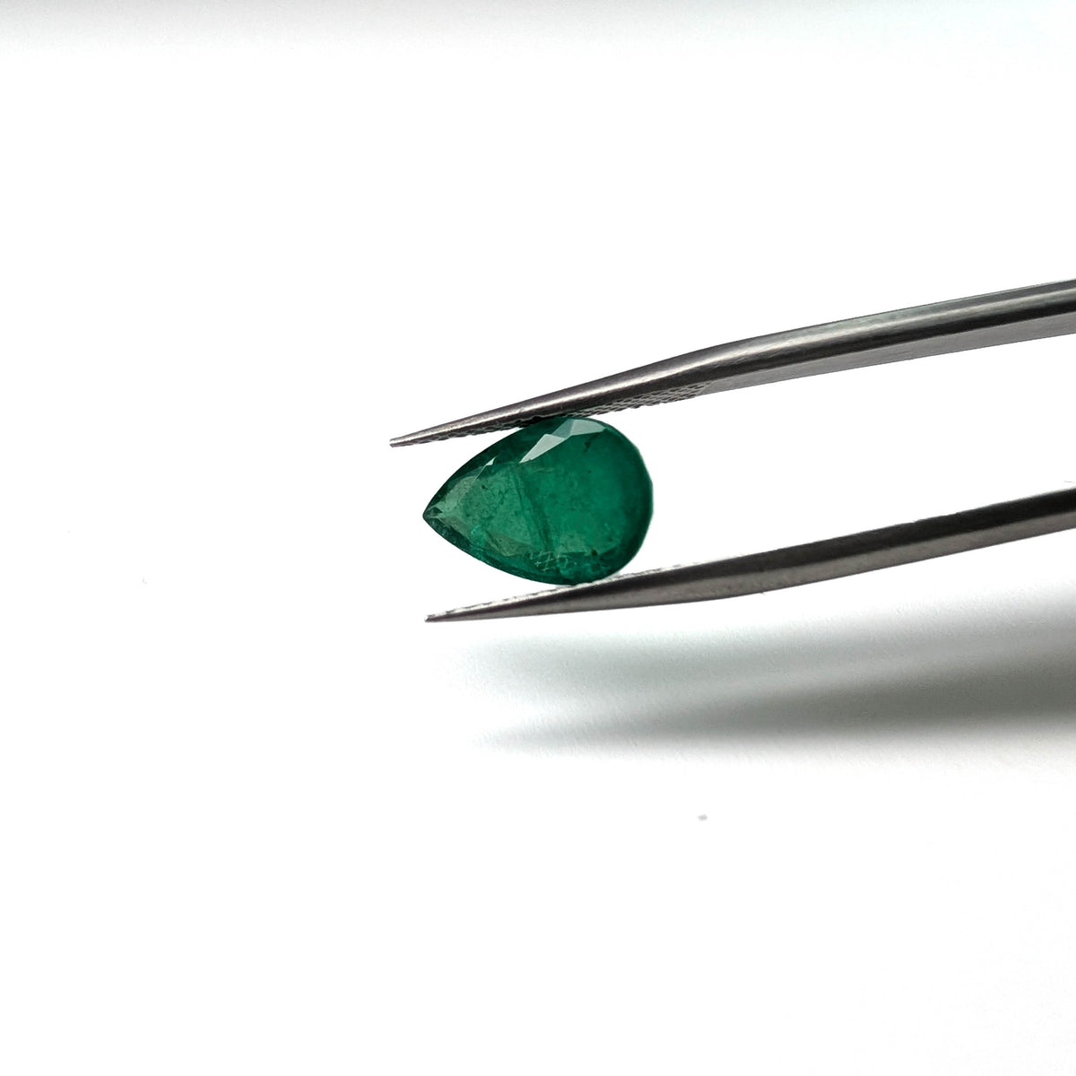 Emerald faceted pear cut gemstone, 2.57ct, held in tweezers, view 2 of 15